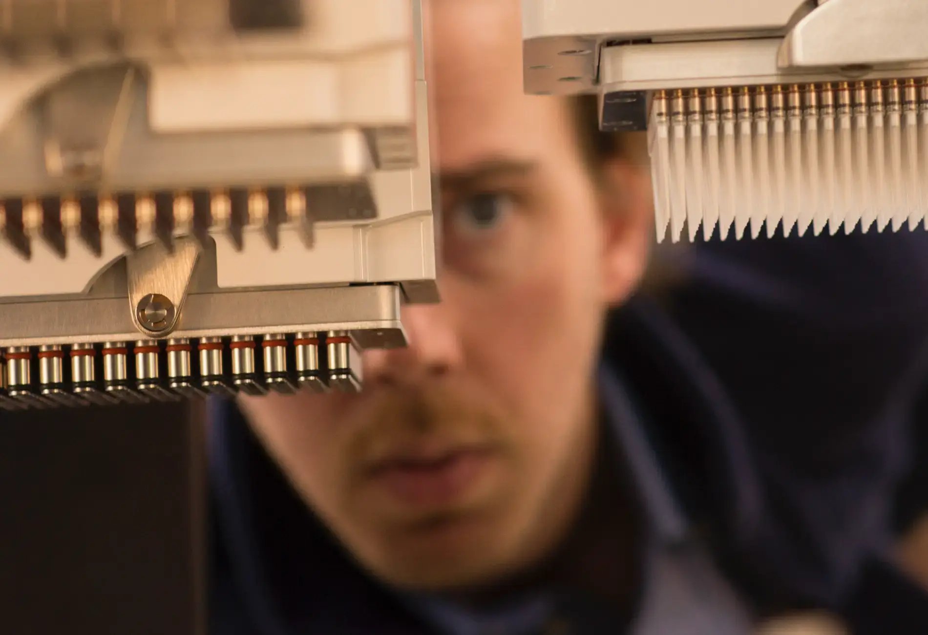 Close-up image of a person observing a liquid handling machine
